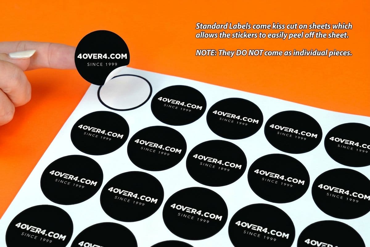 Round logo stickers on a sheet beside a laptop, printed by 4OVER4