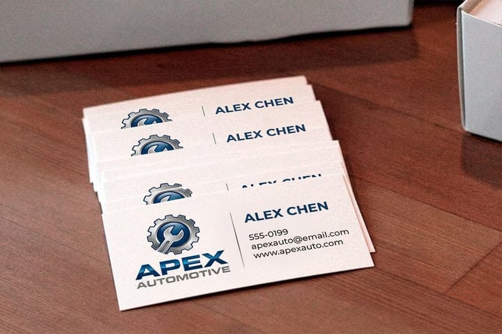 Automotive business cards from 4OVER4 handed across a dealership desk