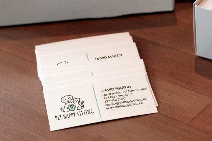 Pet sitting business cards printed by 4OVER4 at a store counter