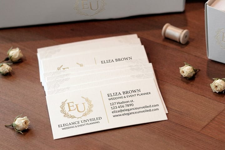 Wedding planner business cards printed by 4OVER4 fanned out on a consultation table