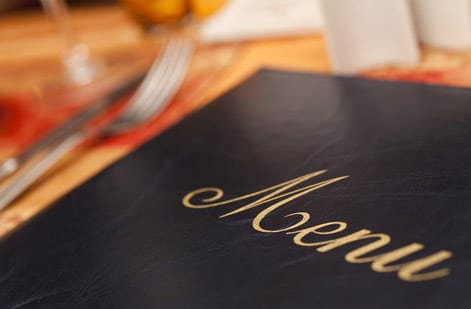 A printed paper placemat set on a restaurant table with plate and cutlery, in the style 4OVER4 prints