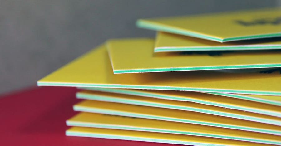 Thick layered business card held to show its rigid colored edge, by 4OVER4