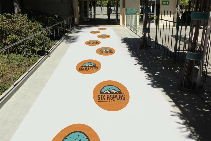 Installer squeegeeing an aluminum floor graphic flat, printed by 4OVER4