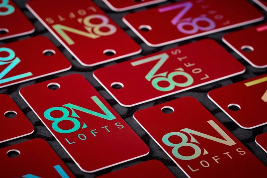 Holographic hangtags printed by 4OVER4 with a rainbow foil finish on dark stock