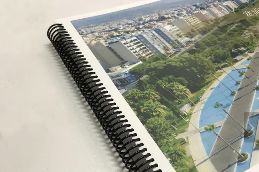 Spiral coil book printed by 4OVER4 lying open flat on a desk