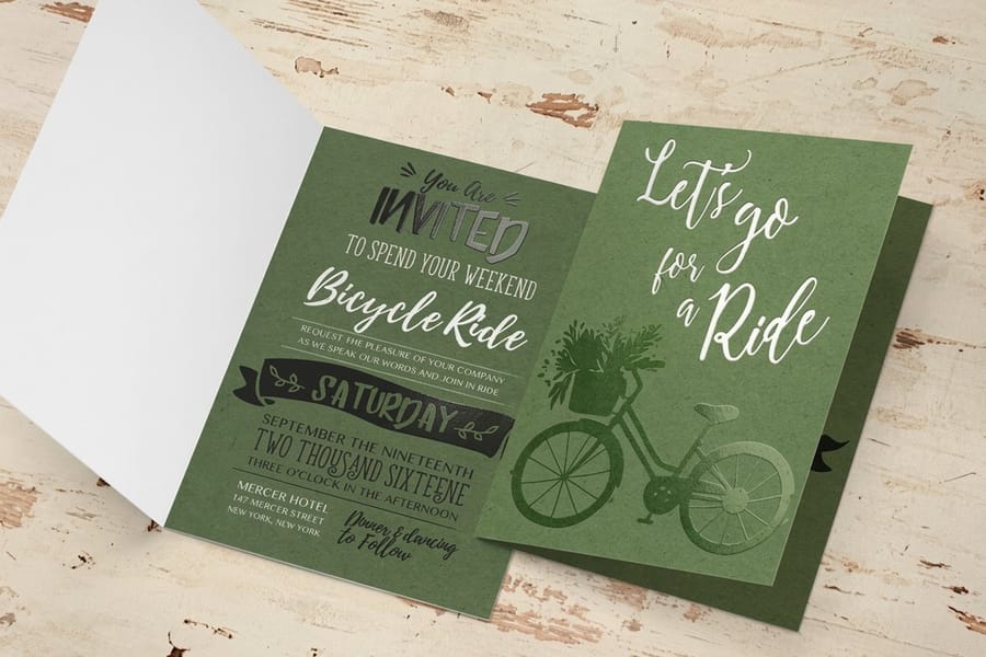 Green bicycle ride greeting cards with spot UV detail printed by 4OVER4 on a wooden table
